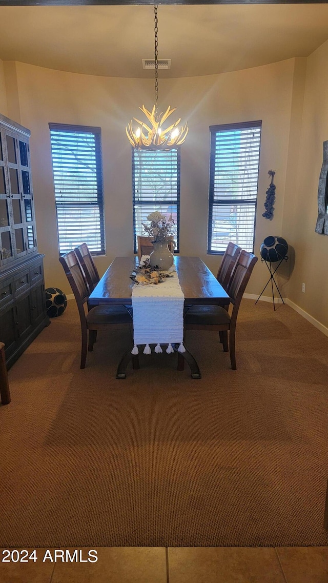 carpeted dining room with an inviting chandelier and plenty of natural light