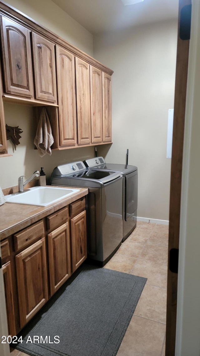 laundry area featuring sink, independent washer and dryer, cabinets, and light tile patterned floors