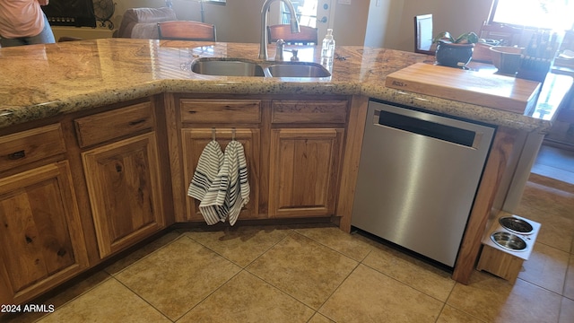 kitchen with sink, light stone countertops, dishwasher, and light tile patterned floors