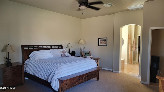 bedroom with connected bathroom, light colored carpet, and ceiling fan