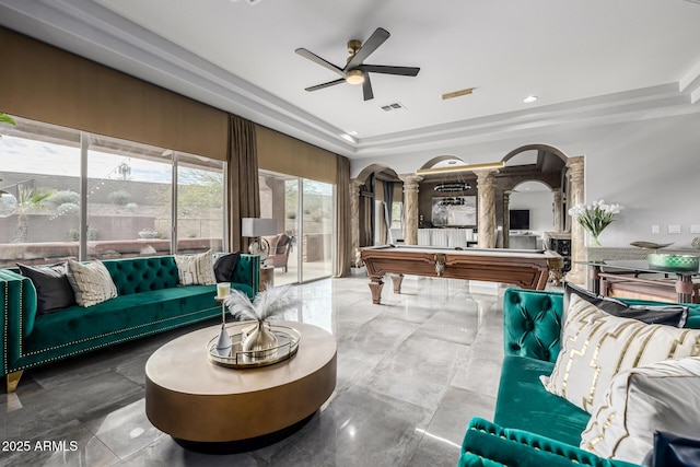 living room with pool table, a raised ceiling, ceiling fan, and ornate columns