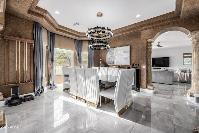 dining area with a tray ceiling, ceiling fan, and ornate columns