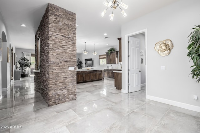 kitchen with dark brown cabinetry, a healthy amount of sunlight, hanging light fixtures, and a notable chandelier