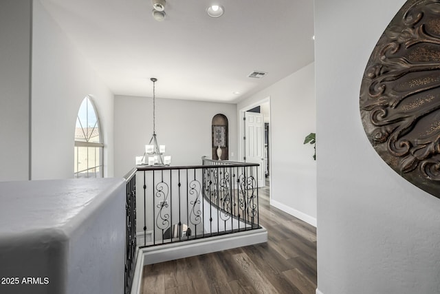 corridor with dark hardwood / wood-style flooring and a notable chandelier