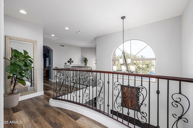 hall featuring dark wood-type flooring and an inviting chandelier