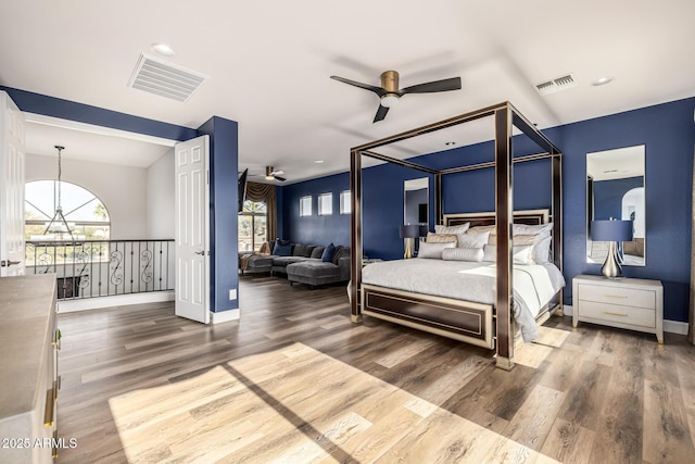 bedroom featuring hardwood / wood-style flooring, multiple windows, and a notable chandelier