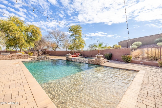 view of pool featuring a patio area, pool water feature, and an in ground hot tub