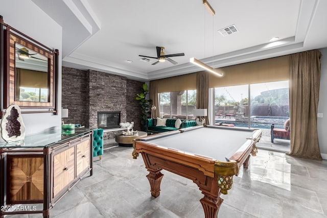 recreation room featuring a stone fireplace, billiards, ceiling fan, and a tray ceiling