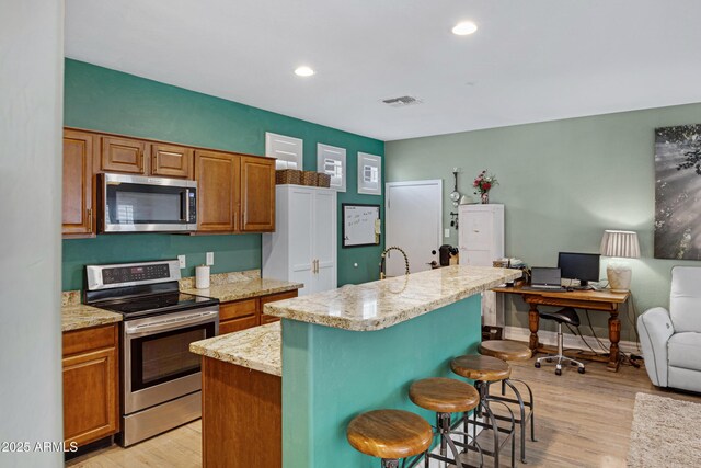 1316 S Minneola Ln, Gilbert, AZ 85296 - kitchen with stainless steel appliances, light wood-style floors, a kitchen island, a breakfast bar area, and recessed lighting