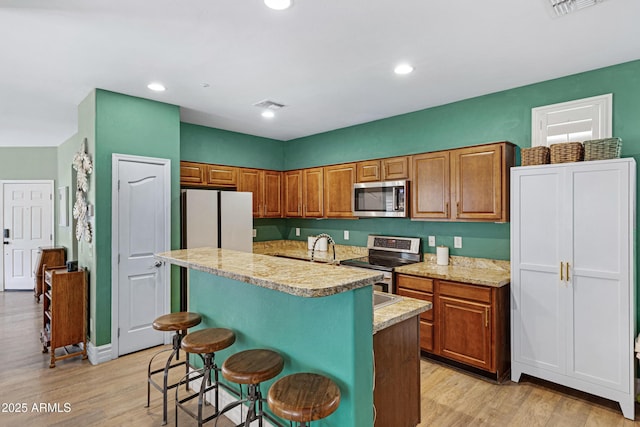 1316 S Minneola Ln, Gilbert, AZ 85296 - kitchen featuring stainless steel appliances, brown cabinetry, light wood-style flooring, and recessed lighting