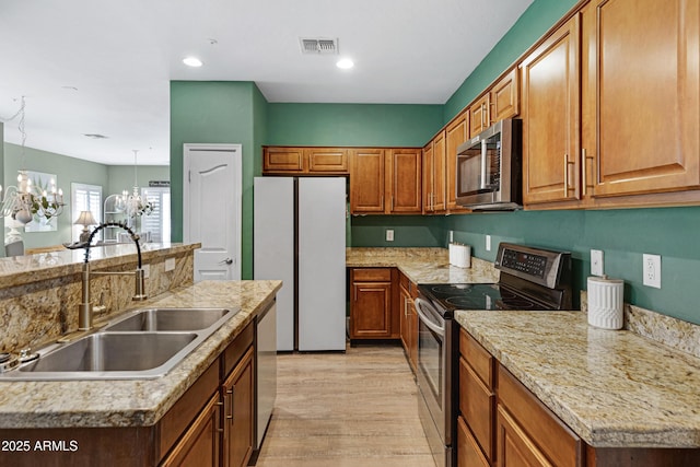 1316 S Minneola Ln, Gilbert, AZ 85296 - kitchen featuring stainless steel appliances, a sink, a chandelier, light wood-type flooring, and brown cabinetry