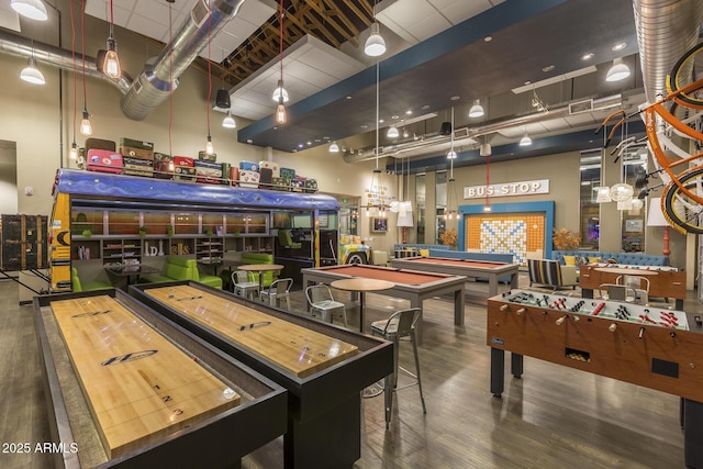 recreation room with dark hardwood / wood-style flooring and a high ceiling