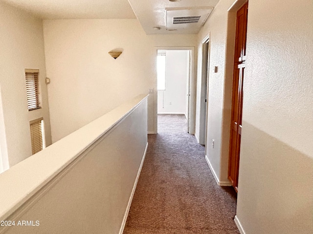 hall featuring dark colored carpet and a wealth of natural light