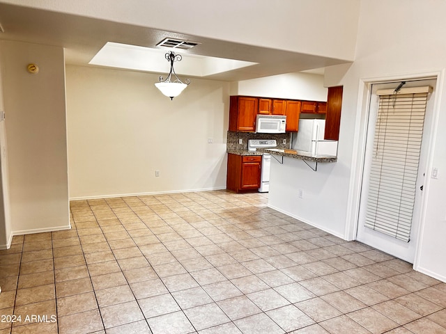 kitchen featuring decorative backsplash, white appliances, light tile patterned floors, hanging light fixtures, and a breakfast bar area