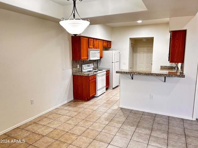 kitchen featuring kitchen peninsula, decorative backsplash, white appliances, pendant lighting, and a breakfast bar area