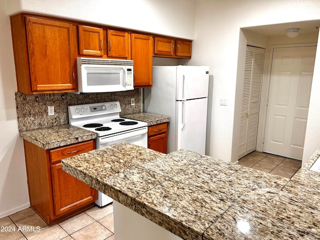 kitchen with tasteful backsplash, light tile patterned flooring, and white appliances