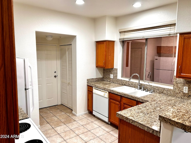 kitchen with decorative backsplash, kitchen peninsula, white appliances, sink, and light tile patterned flooring