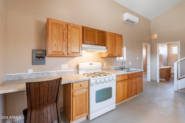 kitchen with a towering ceiling, a wall mounted AC, sink, and gas range gas stove