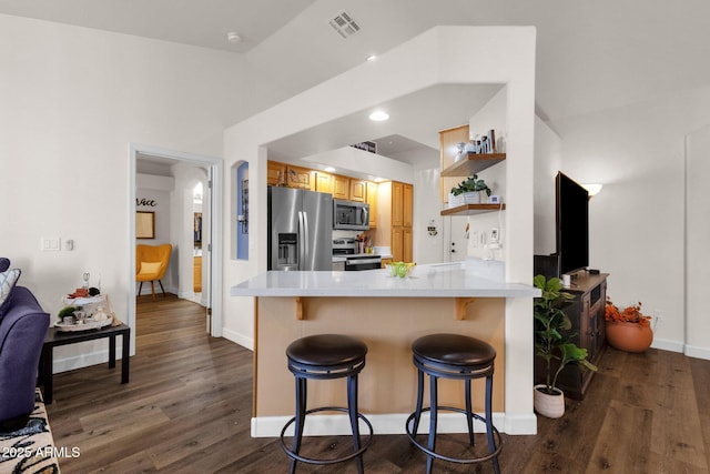 kitchen with a kitchen breakfast bar, dark hardwood / wood-style flooring, kitchen peninsula, and appliances with stainless steel finishes