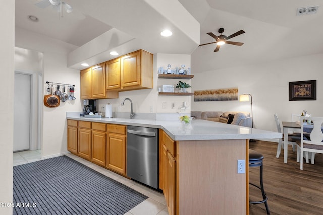 kitchen with kitchen peninsula, a kitchen breakfast bar, vaulted ceiling, light tile patterned floors, and dishwasher