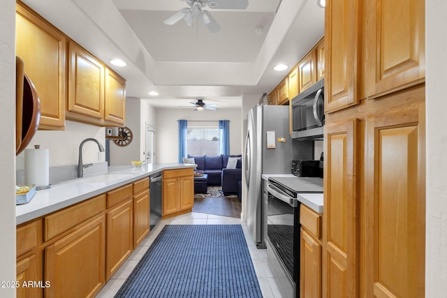 kitchen featuring ceiling fan, sink, kitchen peninsula, light tile patterned floors, and appliances with stainless steel finishes