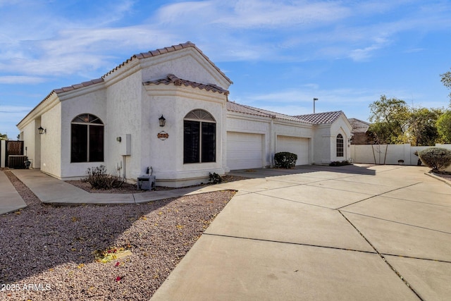 mediterranean / spanish-style home with central AC unit and a garage