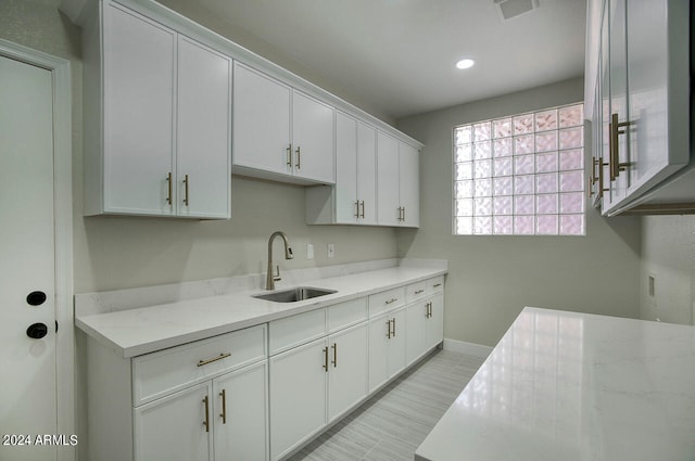 kitchen with light stone counters, sink, and white cabinets