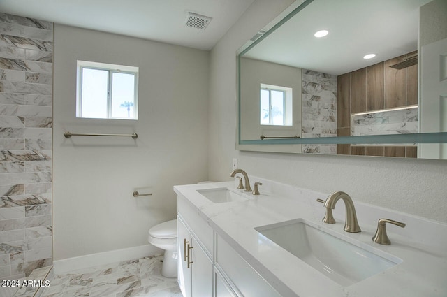 bathroom with toilet, tiled shower, and vanity