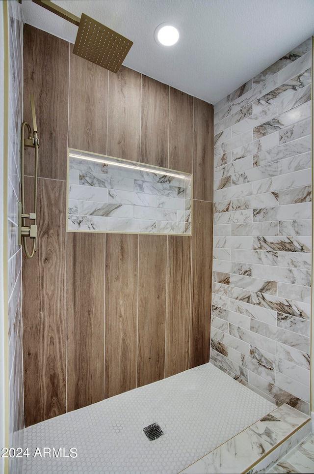 bathroom with tiled shower and a textured ceiling