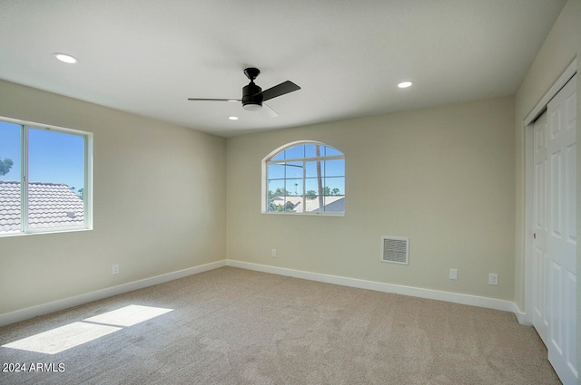 unfurnished bedroom with a closet, light colored carpet, and ceiling fan