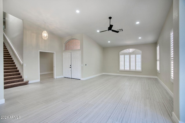 unfurnished living room with a high ceiling, light wood-type flooring, and ceiling fan