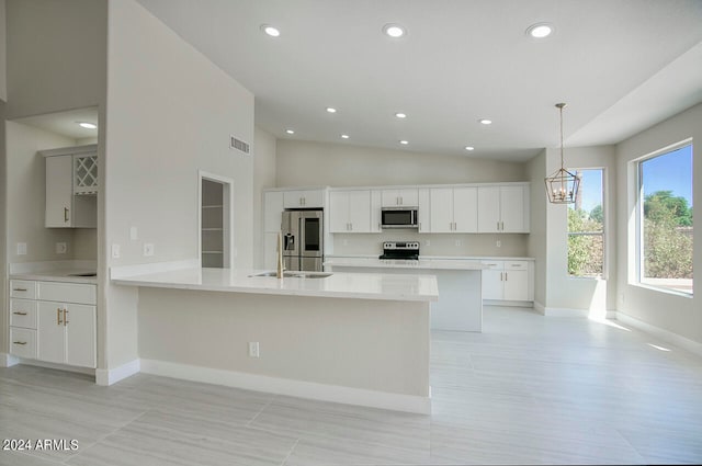 kitchen featuring lofted ceiling, stainless steel appliances, kitchen peninsula, pendant lighting, and white cabinetry