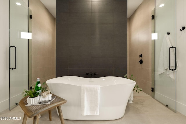 bathroom with tile walls, a freestanding tub, and a shower stall