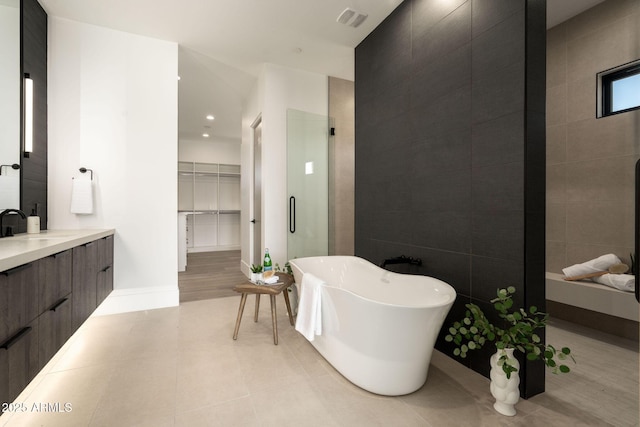 bathroom with a freestanding tub, visible vents, tile walls, tile patterned flooring, and vanity