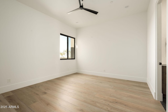 spare room with baseboards, light wood-style floors, and a ceiling fan