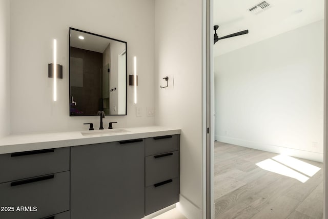 bathroom featuring visible vents, wood finished floors, baseboards, ceiling fan, and vanity