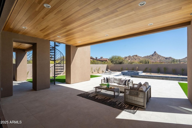 view of patio / terrace with an outdoor living space, a fenced backyard, a mountain view, and a pool with connected hot tub