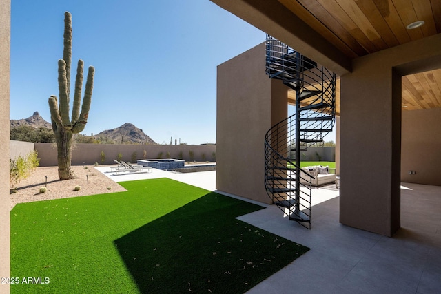 view of yard featuring a fenced backyard, a mountain view, and a patio