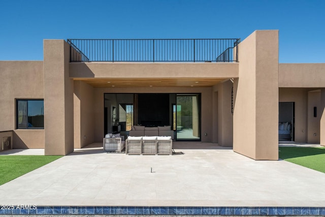 rear view of property with stucco siding, a patio, an outdoor hangout area, and a balcony