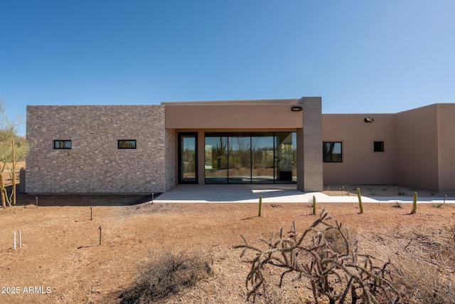 rear view of property featuring a patio and stucco siding