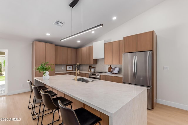 4532 E Sandra Ter, Phoenix, AZ 85032 - kitchen with stainless steel appliances, light wood-style floors, a kitchen bar, light countertops, and lofted ceiling