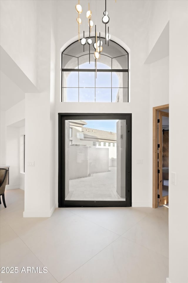 foyer featuring a notable chandelier, tile patterned floors, and a high ceiling