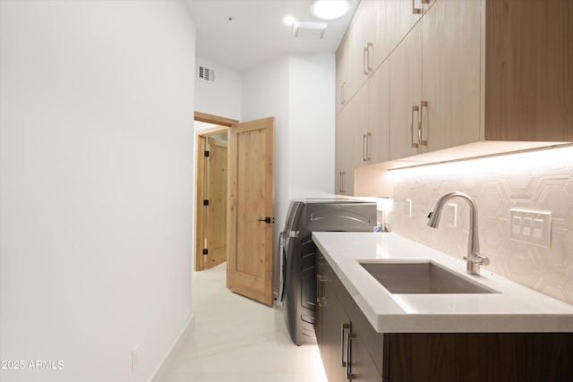 washroom with cabinets, washer / dryer, and sink