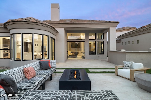 back house at dusk with a patio and a fire pit