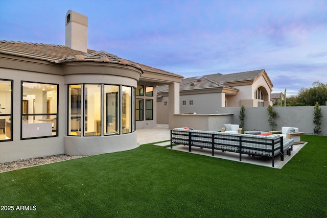 back house at dusk featuring a yard, an outdoor hangout area, and a patio area