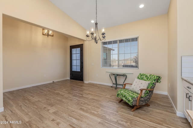 unfurnished room with lofted ceiling, a chandelier, and light wood-type flooring