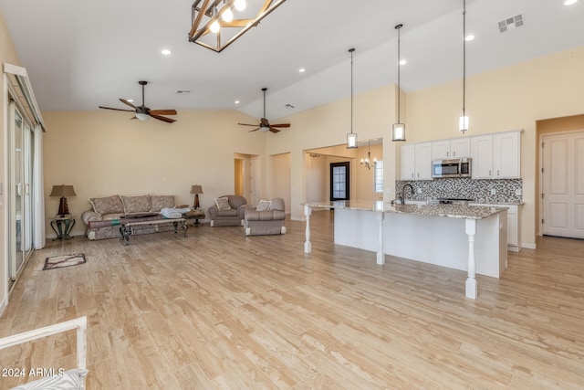 kitchen with a kitchen breakfast bar, white cabinetry, light stone countertops, light hardwood / wood-style floors, and decorative light fixtures