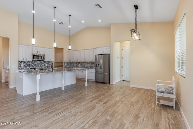 kitchen featuring white cabinets, stainless steel appliances, stone countertops, and light wood-type flooring