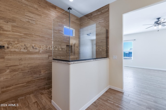 bathroom with tiled shower, hardwood / wood-style floors, and ceiling fan