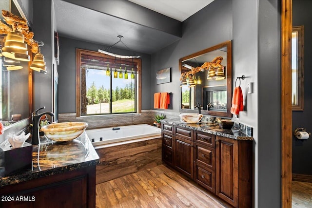 bathroom featuring hardwood / wood-style flooring, vanity, and a relaxing tiled tub